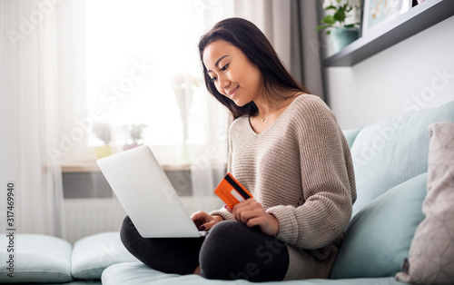 Asian girl making online payment using laptop for shopping at home photo