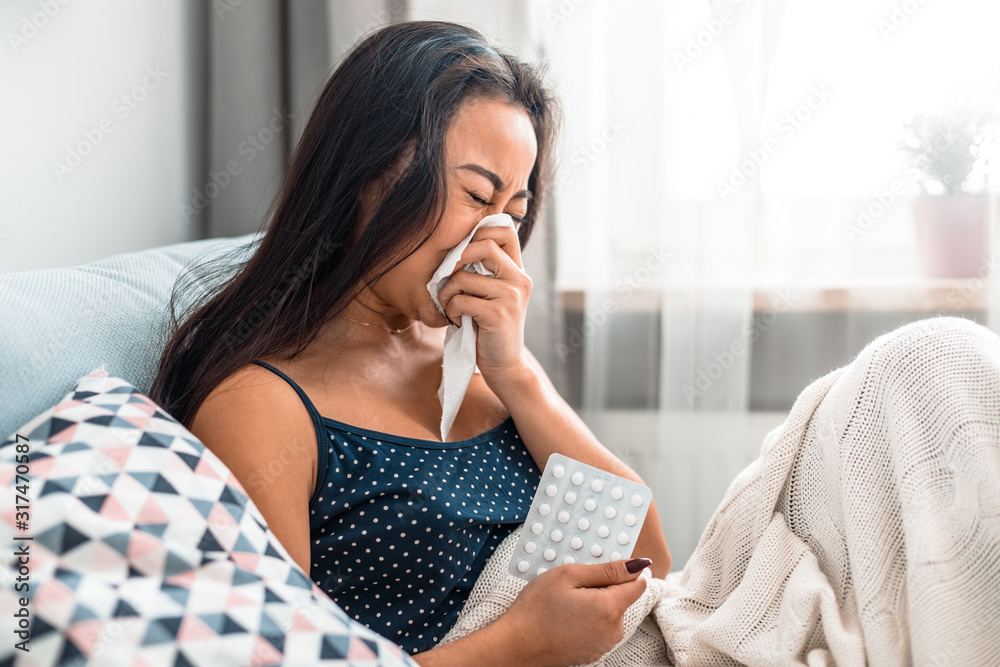 Asian girl suffering from cold sitting on bed at home Asian girl suffering from cold sitting on bed at home