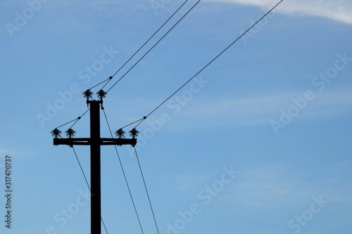 Alte Strommasten aus Holz als Silhouette vor blauen Hintergrund - Stromversorgung auf dem Land