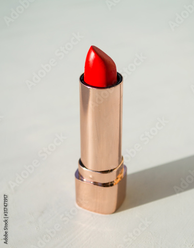 Red lipstick in golden tube on white background  luxury cosmetic accessory.