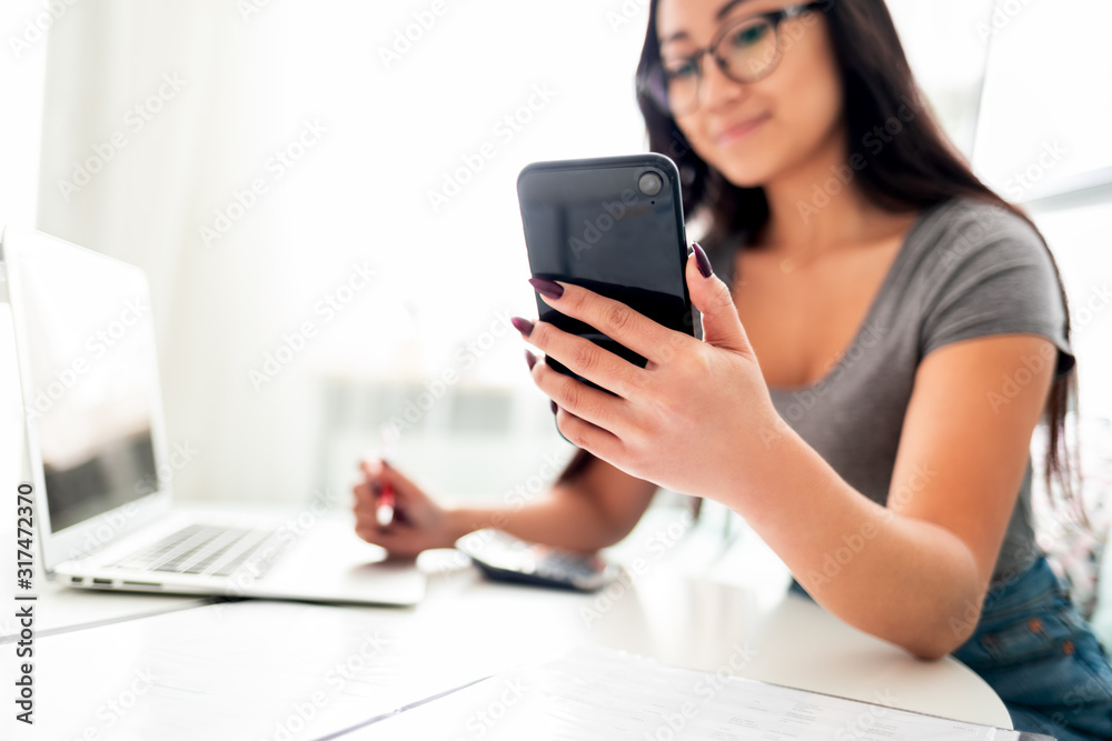 Asian woman using smartphone app and laptop for calaulating home budget finance taxes Asian woman using smartphone app and laptop for calaulating home budget finance taxes
