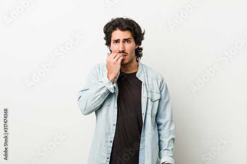 Young handsome man against a white background biting fingernails, nervous and very anxious.