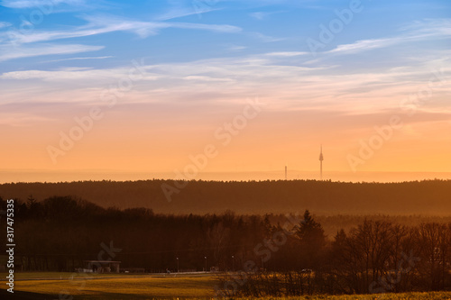 Beautiful rural sunset landscape with the television tower of Nuremberg in the background. Seen in Bavaria, Germany in January from Tauchersreuth.
