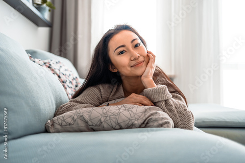 Relaxed asian girl lying on sofa at home in calm leisure time