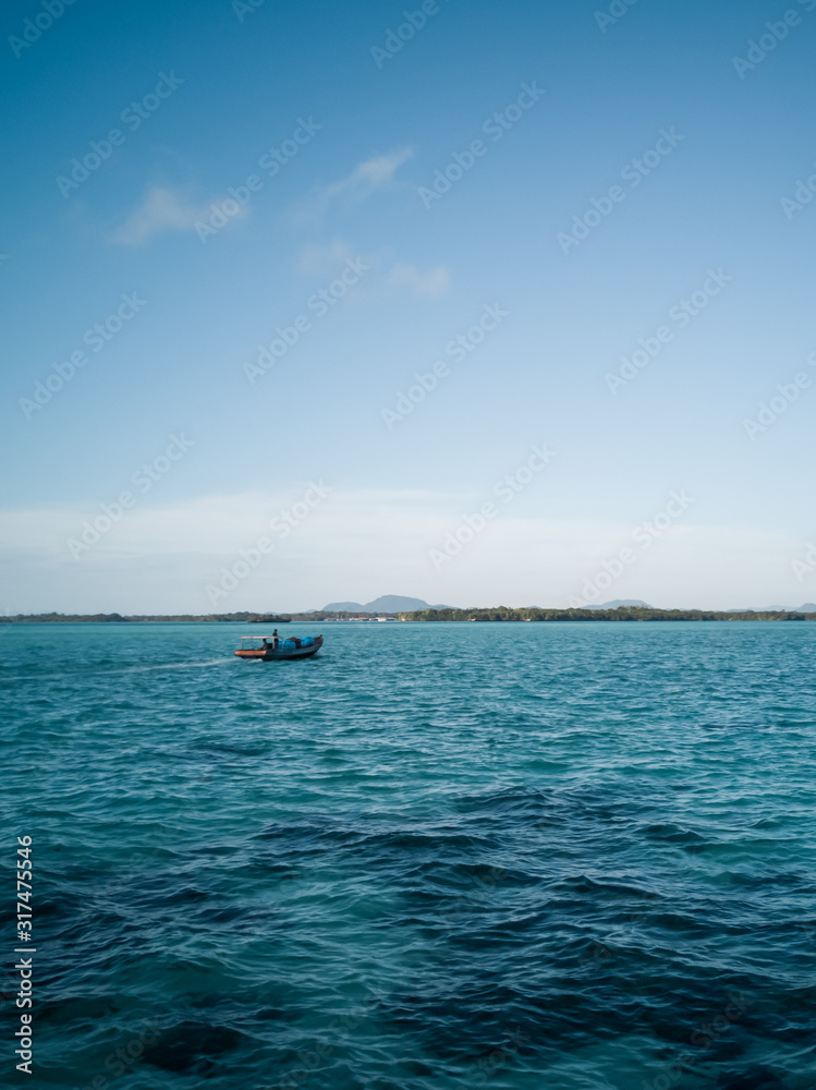 speedboat moving fast over waving sea very beautiful day. fast ship moving straight over blue water in background showing shore island and blue sky.