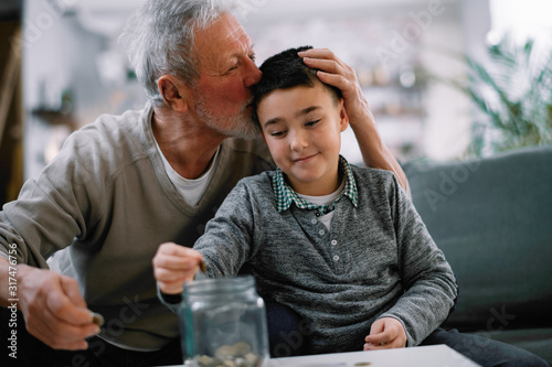 Grandpa and grandson saving money. Grandfather teaching grandchild how to save money.  