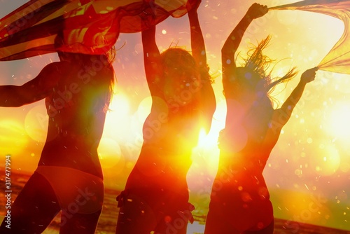 Team of young women friends walking on the sea shore