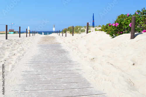 Wooden walkway to the beach between sand dunes.