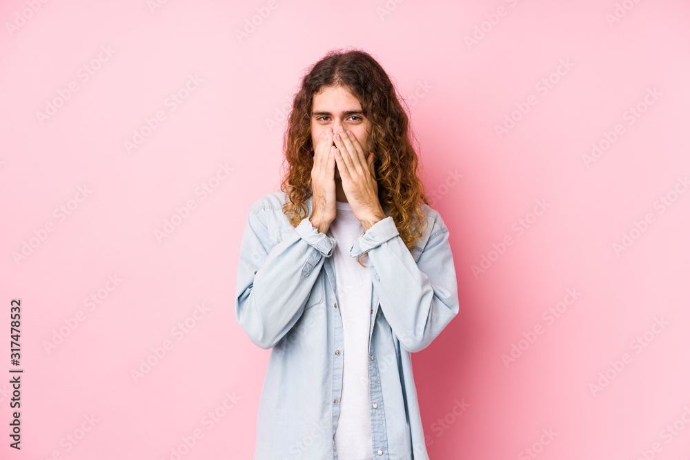 Long hair man posing isolated laughing about something, covering mouth with hands. Long hair man posing isolated laughing about something, covering mouth with hands.