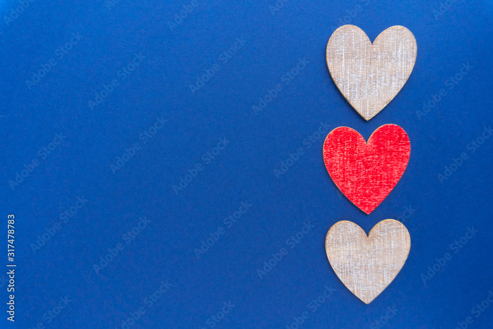 Valentine day background. Flat lay with three wooden hearts at classic blue background.