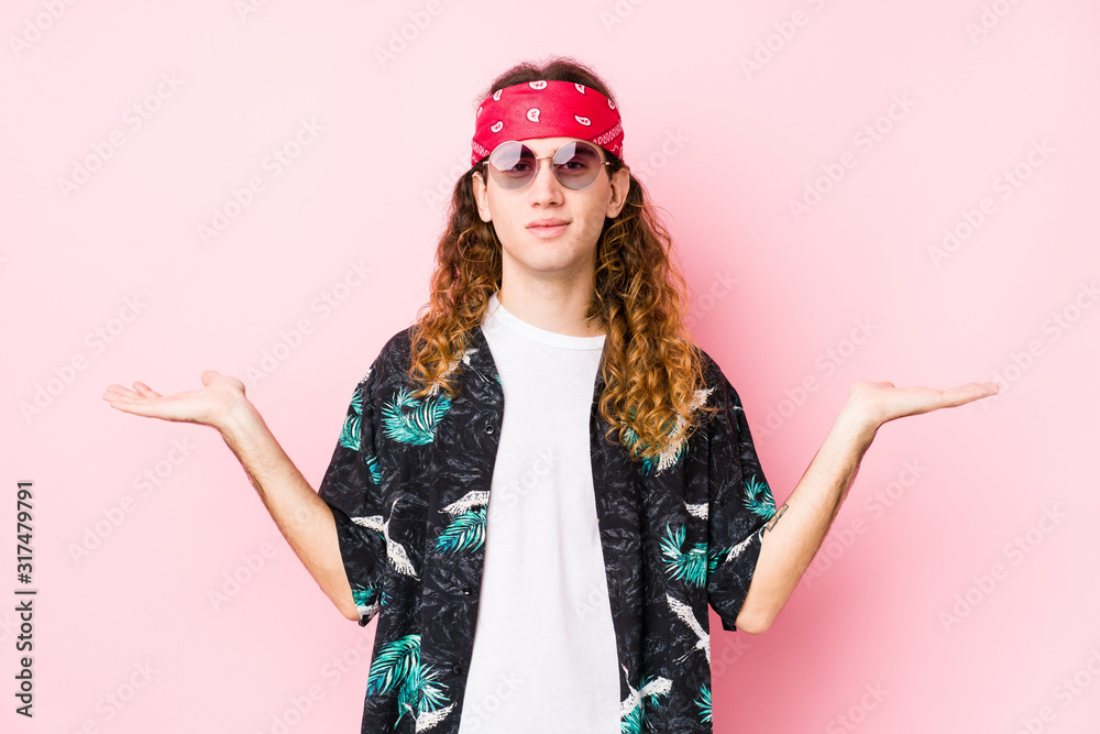 Young hippie caucasian man isolated makes scale with arms, feels happy and confident. Young hippie caucasian man isolated makes scale with arms, feels happy and confident.
