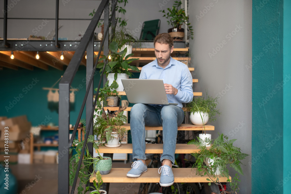 Fototapeta premium Man using a computer while sitting on stairs