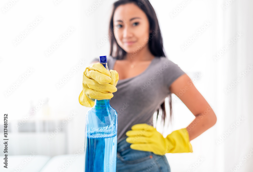 Young asian girl with gloves and spray cleaning house Young asian girl with gloves and spray cleaning house