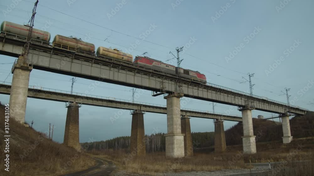 Freight train passes on a railway bridge with columns Freight train passes on a railway bridge with columns