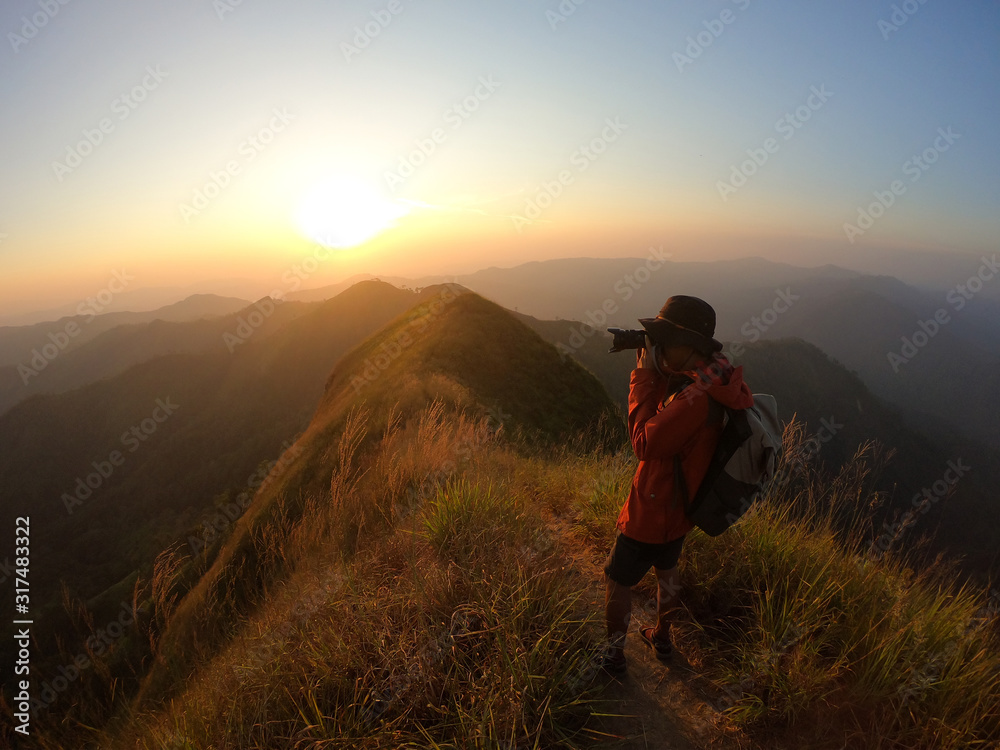 Male photographer taking photo on mountain at sunset