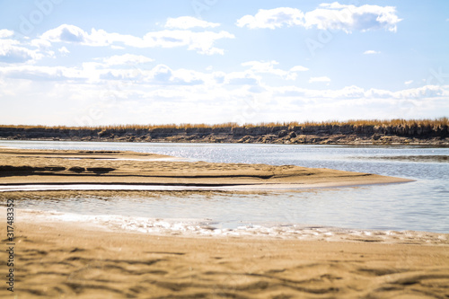river bank with sand dunes with defocused shallow waters of river on the background