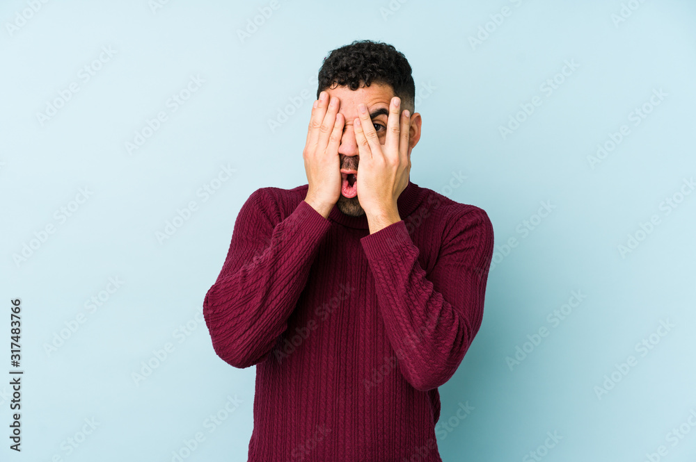 Young mixed race arabic man isolated blink through fingers frightened and nervous. Young mixed race arabic man isolated blink through fingers frightened and nervous.
