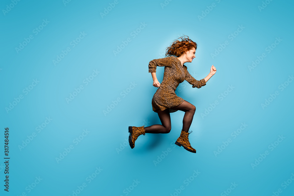 Obraz premium Full body profile photo of funny lady jump high speed rushing autumn winter discounts shopping wear pretty short leopard pattern dress boots isolated blue color background