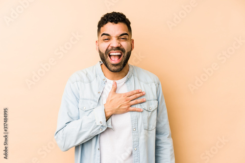 Young mixed race arabic man isolated laughs out loudly keeping hand on chest.