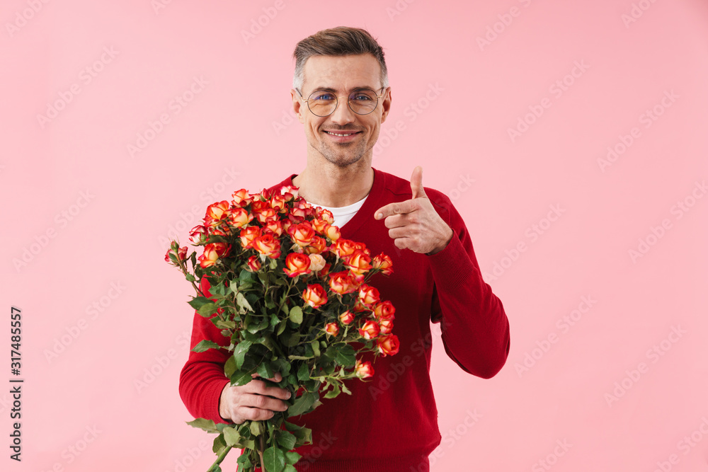 Portrait of handsome man wearing eyeglasses pointing finger at flowers Portrait of handsome man wearing eyeglasses pointing finger at flowers