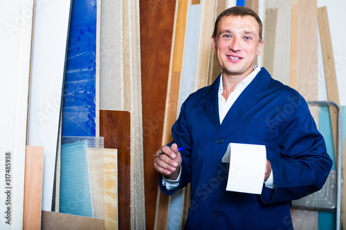 portrait of man in uniform choosing compressed densified wood in picture framing atelier photo