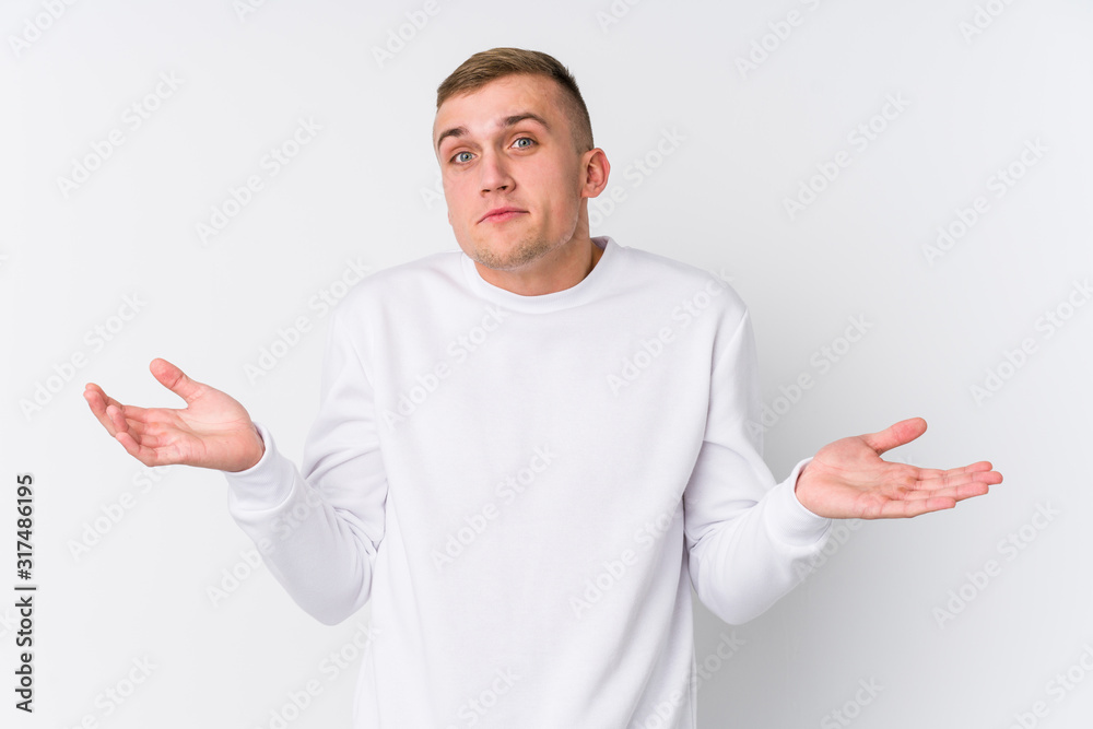 Young caucasian man on white background doubting and shrugging shoulders in questioning gesture. Young caucasian man on white background doubting and shrugging shoulders in questioning gesture.