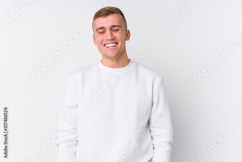 Young caucasian man on white background laughs and closes eyes, feels relaxed and happy. © Asier