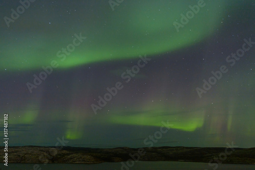 Aurora borealis over the hills. At night in the sky in the north. © Moroshka