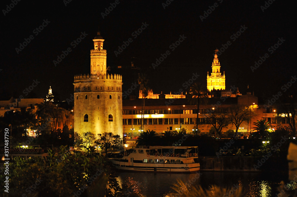 Cityscape of Seville by night with the Torre del Oro (Golden Tower), the Giralda tower and Guadalquivir river, Andalusia, Spain