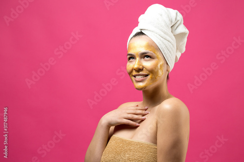 Beauty portrait of woman in white towel on head with gold nourishing mask on face. Skincare cleansing eco organic cosmetic spa relax concept.