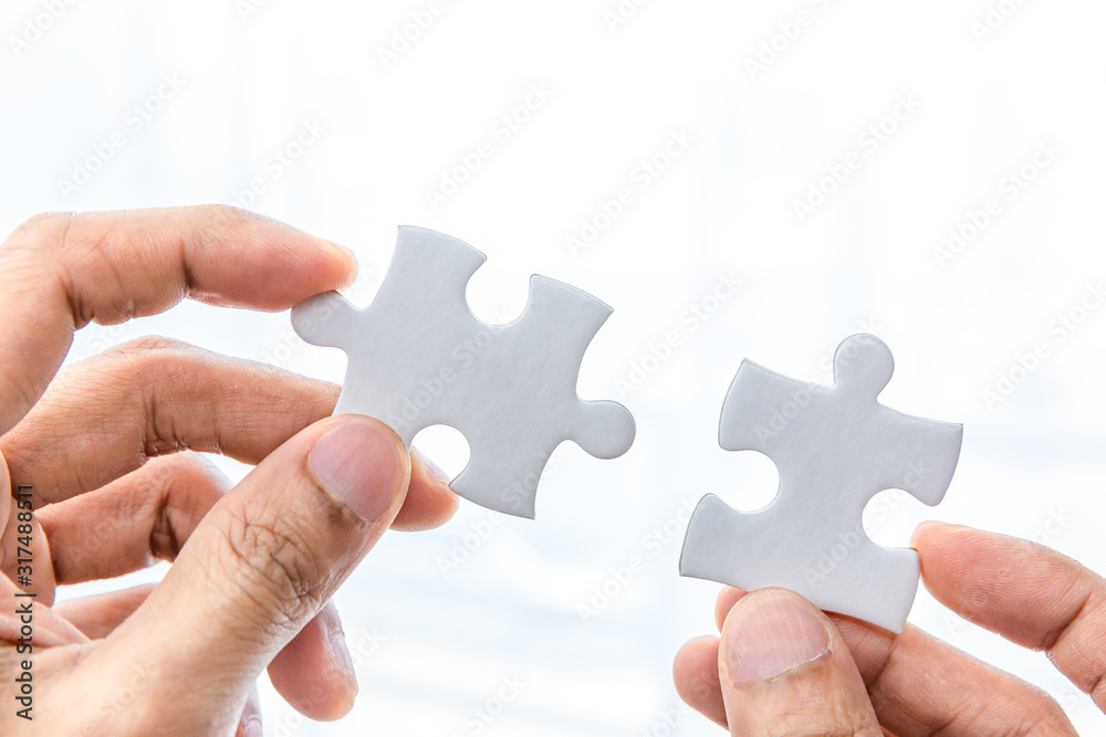 Hand holding two pieces of jigsaw connecting couple puzzle Hand holding two pieces of jigsaw connecting couple puzzle