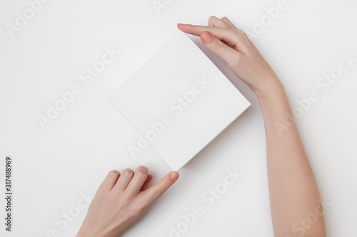 Mock up of white present box in women's hands on the white background