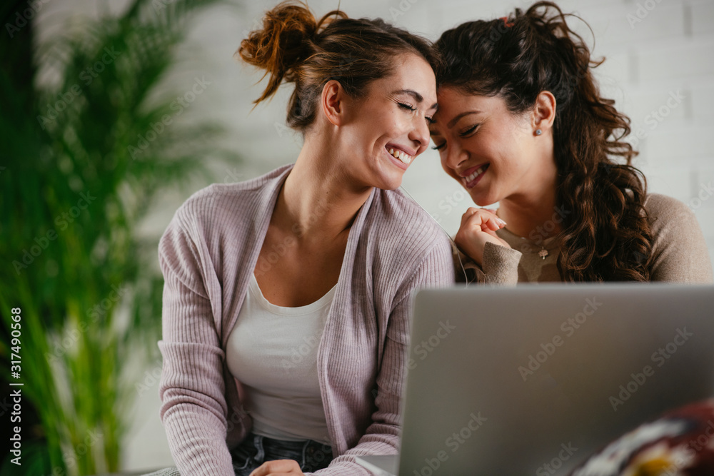 Two friend sitting on couch with laptop and listening music. Sisters having fun. Two friend sitting on couch with laptop and listening music. Sisters having fun.
