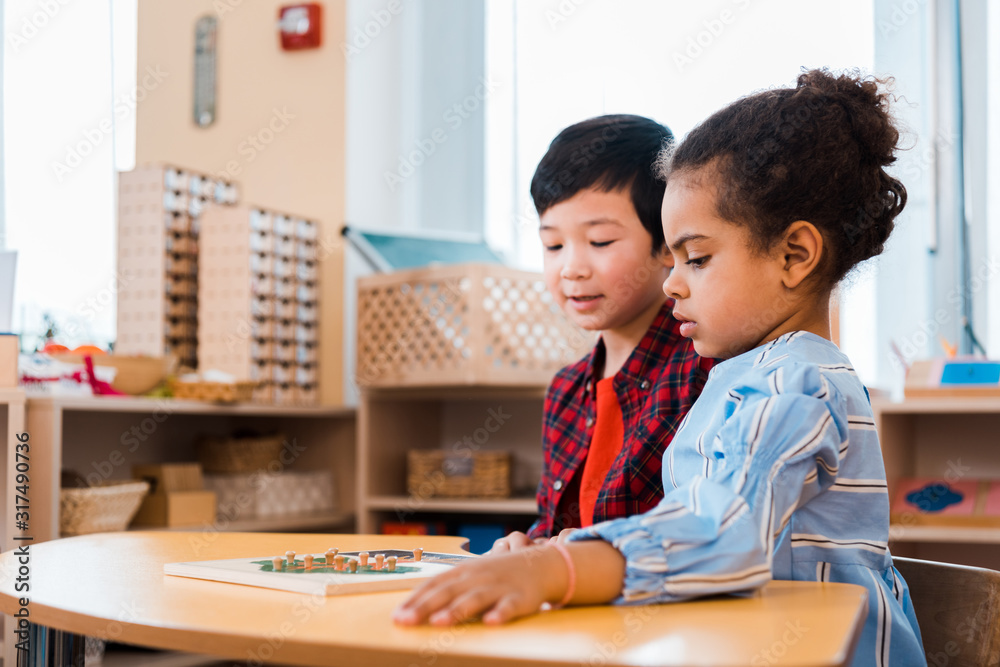 Side view of children folding educational game in montessori school Side view of children folding educational game in montessori school