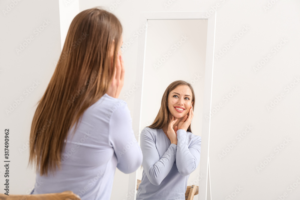 Beautiful young woman looking in mirror at home Stock Photo | Adobe Stock
