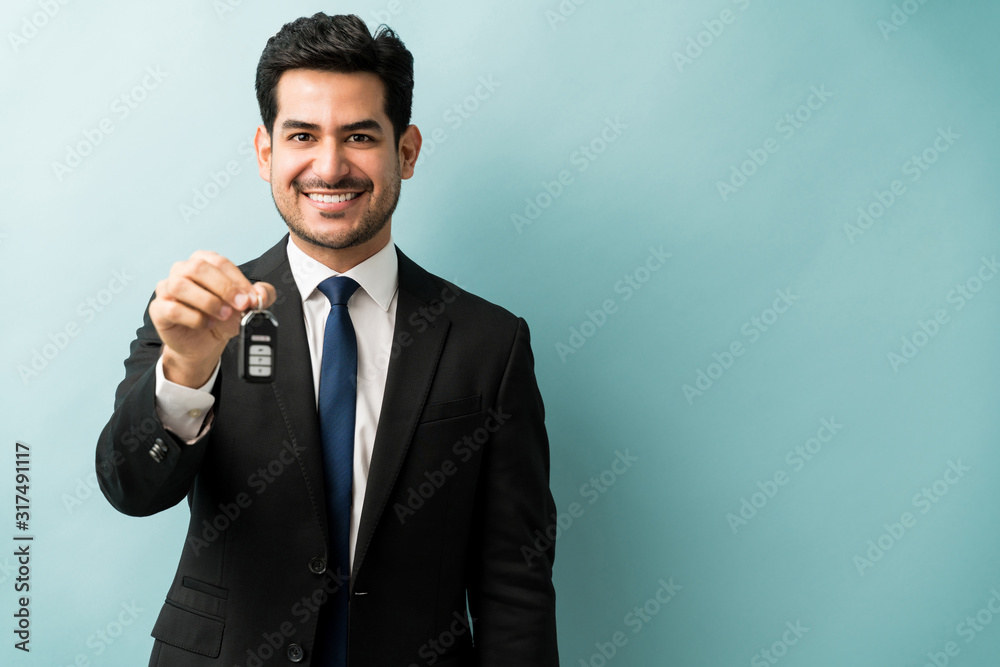 Male Dealer Offering Car Key Against Colored Background Male Dealer Offering Car Key Against Colored Background