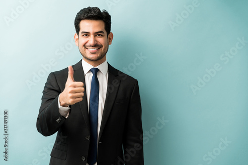Portrait Of Businessman Showing Hand Sign In Studio