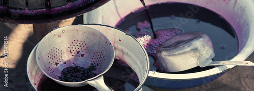 Winepress with red must and helical screw. Traditional old technique of wine making. Filtering grape must. Tinted panoramic image. photo