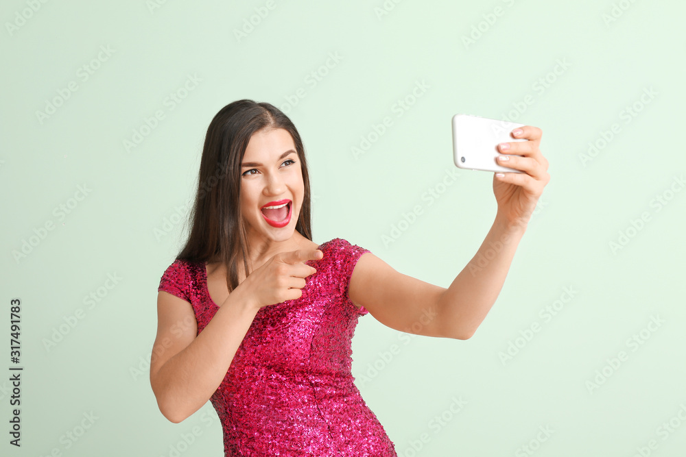 Beautiful young woman taking selfie on color background Beautiful young woman taking selfie on color background