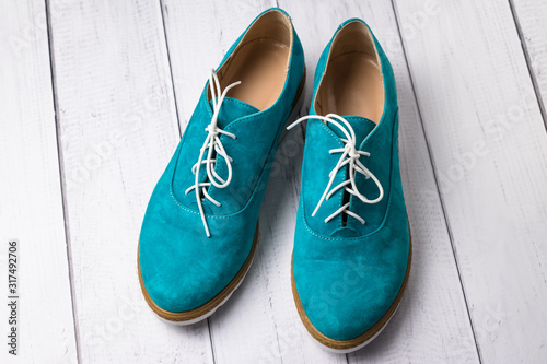 Pair of green casual suede shoes with laces on wooden background. Turquoise women's oxfords, oxford shoe.