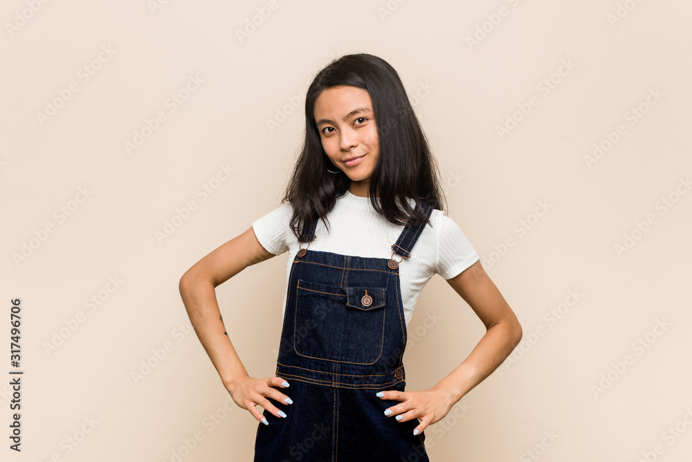 Young cute chinese teenager Young blonde woman wearing a coat against a pink background confident keeping hands on hips. Young cute chinese teenager Young blonde woman wearing a coat against a pink background confident keeping hands on hips.