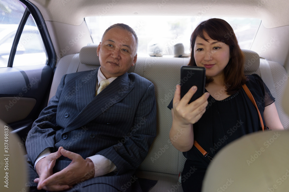Mature Asian businessman and mature Asian woman riding car together Mature Asian businessman and mature Asian woman riding car together