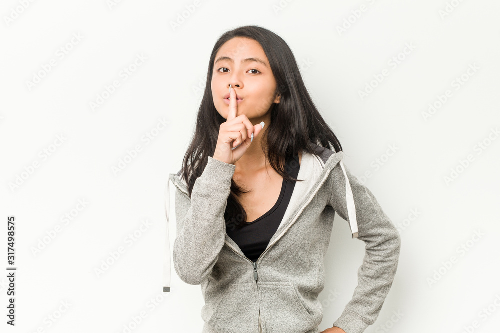 Young fitness chinese woman keeping a secret or asking for silence. Young fitness chinese woman keeping a secret or asking for silence.