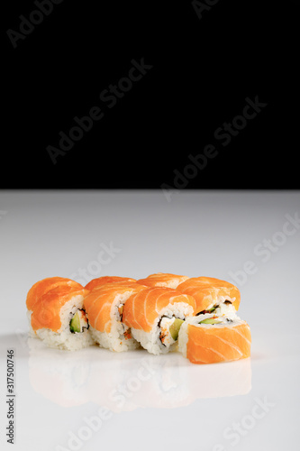 delicious Philadelphia sushi with avocado, creamy cheese, salmon and masago caviar on white surface isolated on black