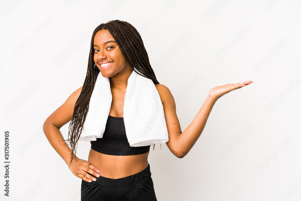 Young african american sport woman isolated showing a copy space on a palm and holding another hand on waist. Young african american sport woman isolated showing a copy space on a palm and holding another hand on waist.