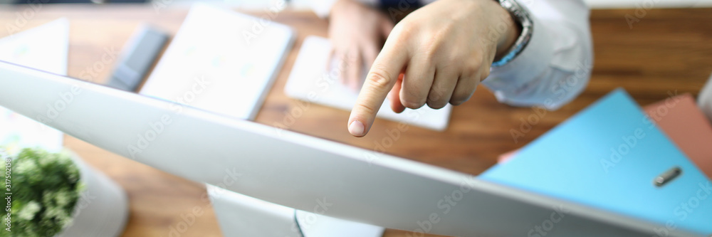 Top view of concentrated manager sitting at workplace. Businessman looking attentively at computer monitor and showing something with finger. Blurred background