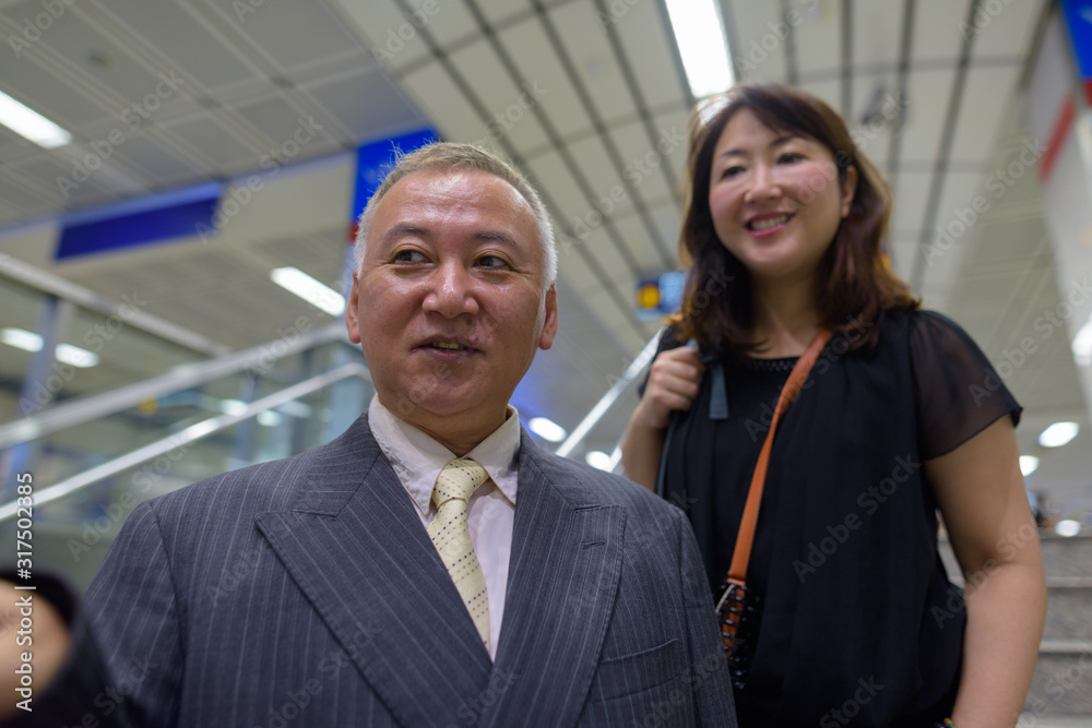 Mature Asian businessman and mature Asian woman at the subway station together Mature Asian businessman and mature Asian woman at the subway station together