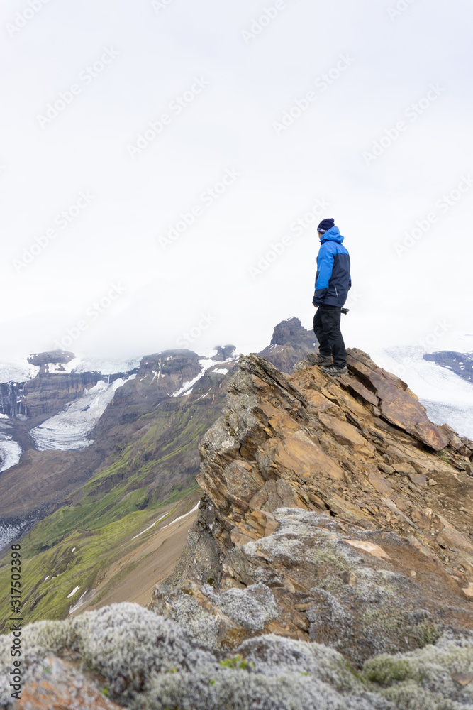  A photographer on the top of the mountain in Iceland. View to a melting glacier tongue of the biggest glacier in Europe called Vatnajökull. 