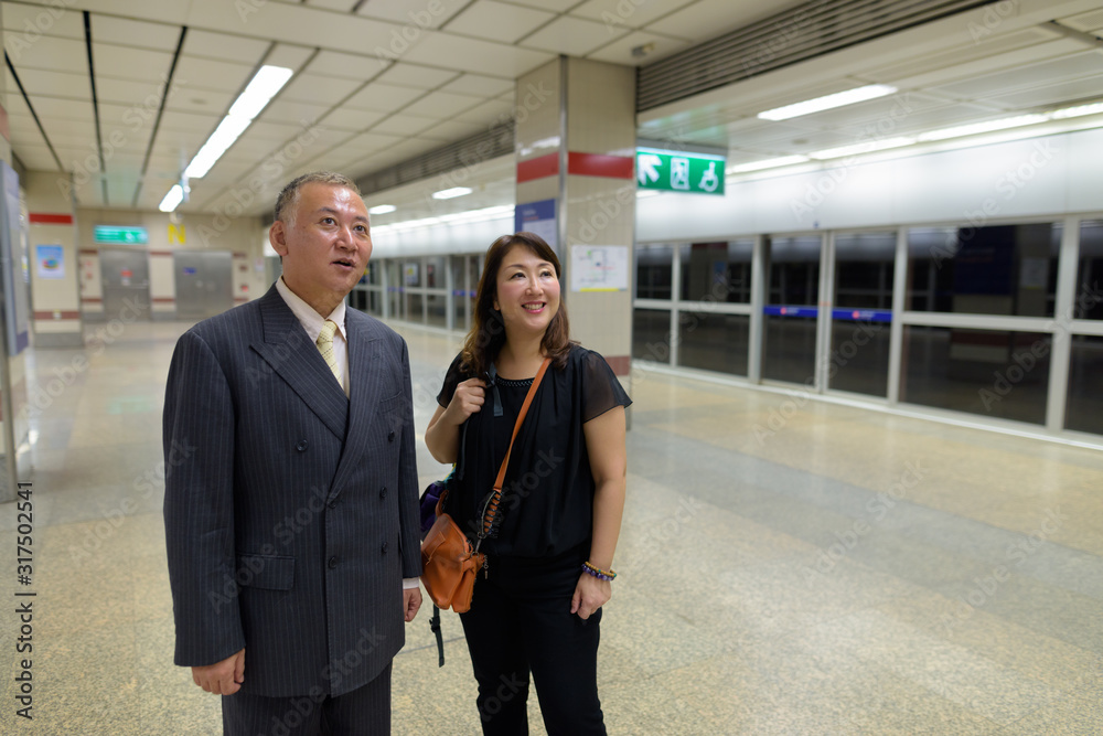 Mature Asian businessman and mature Asian woman at the subway station together