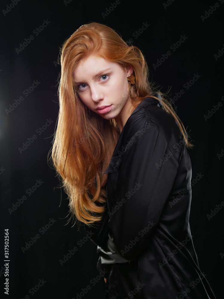 Fototapeta premium young girl with long red hair on a black background